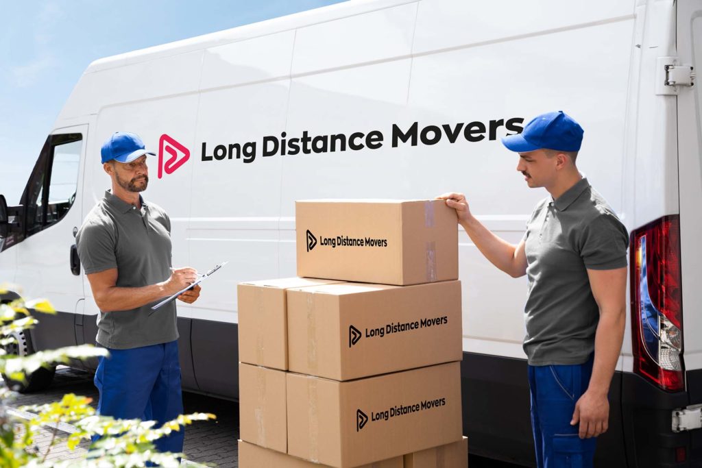 A smiling long-distance mover next to a pile of boxes