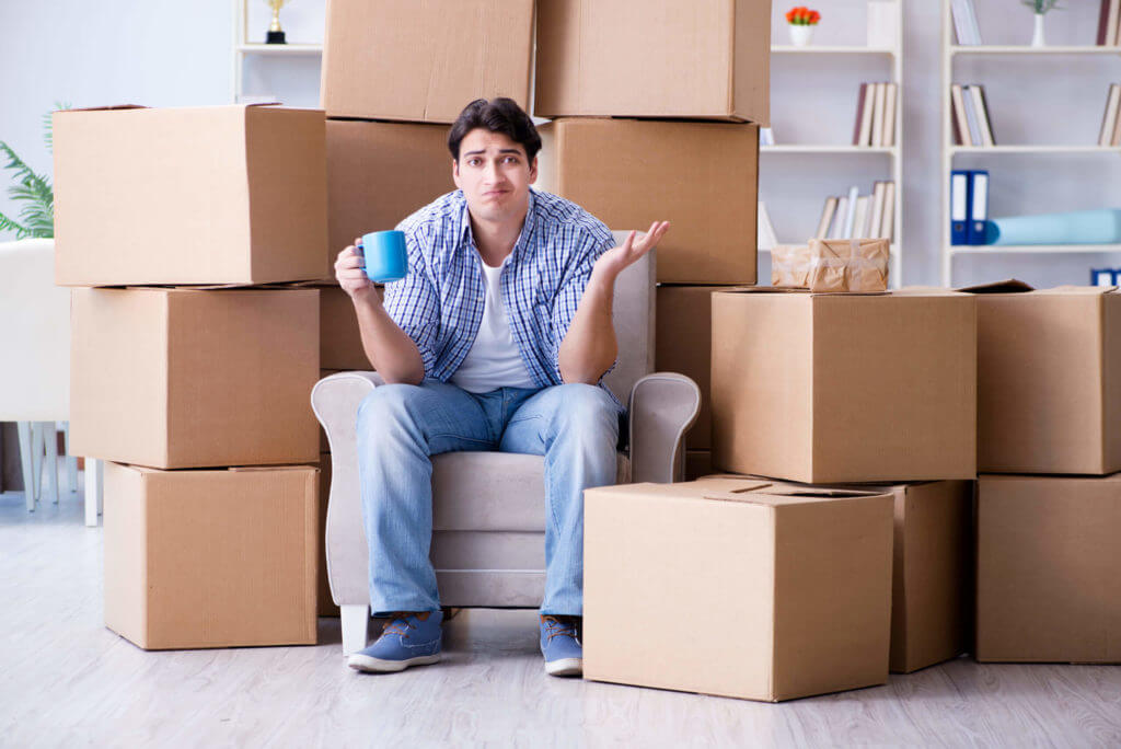 Young man, relocating into a new house with boxes