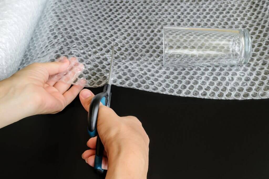 Person cutting bubble wrap before long-distance moving