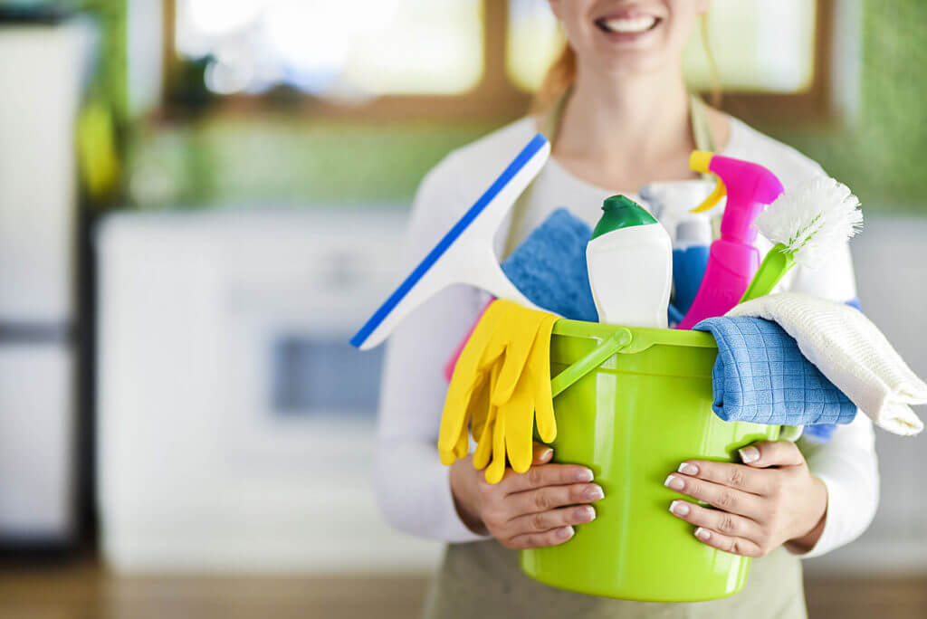 A person holding a bucket of cleaning supplies