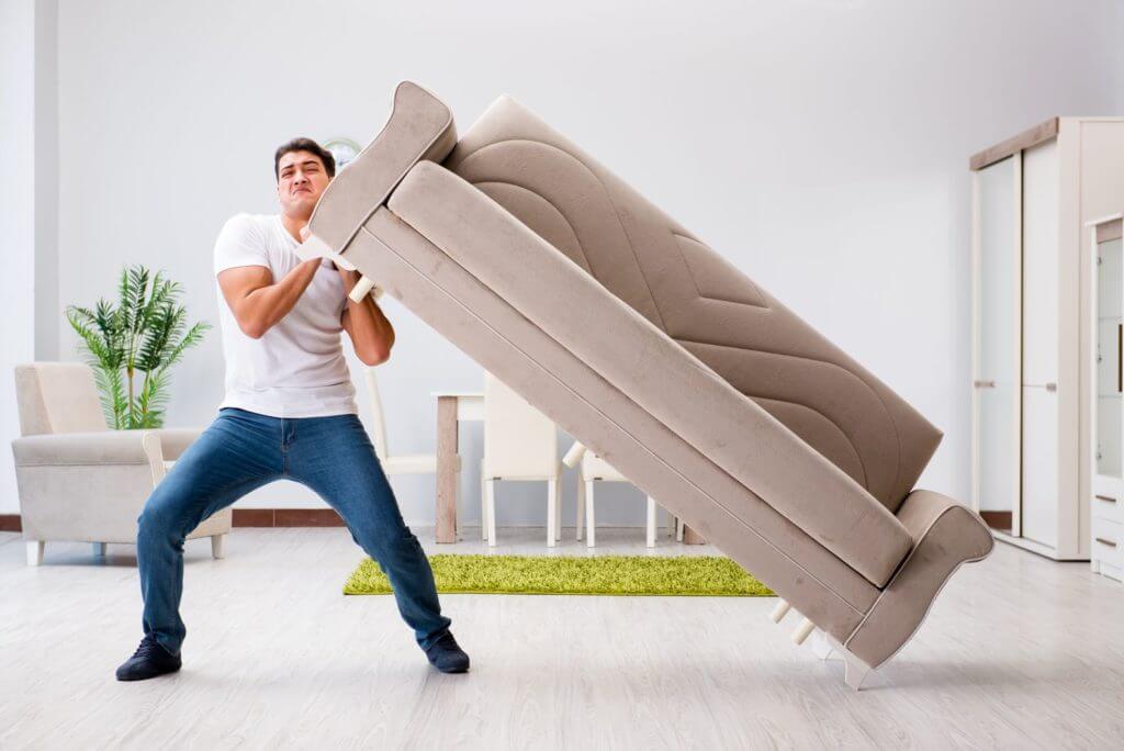 A man trying to lift a sofa