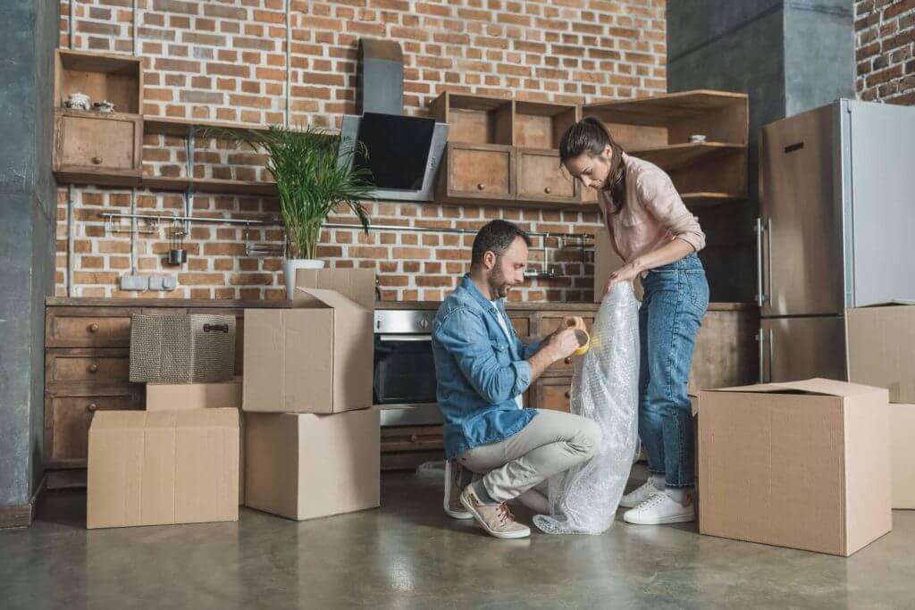 A man and a woman at home packaging an object before calling a relocation company