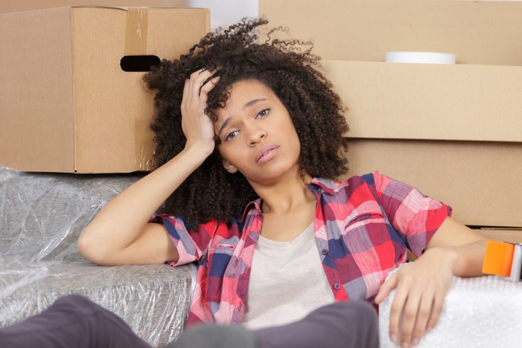 A stressed girl leaning on boxes for long-distance moving 