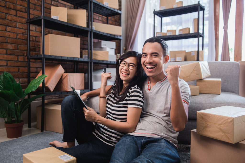 A young couple smiling and cheering while packing