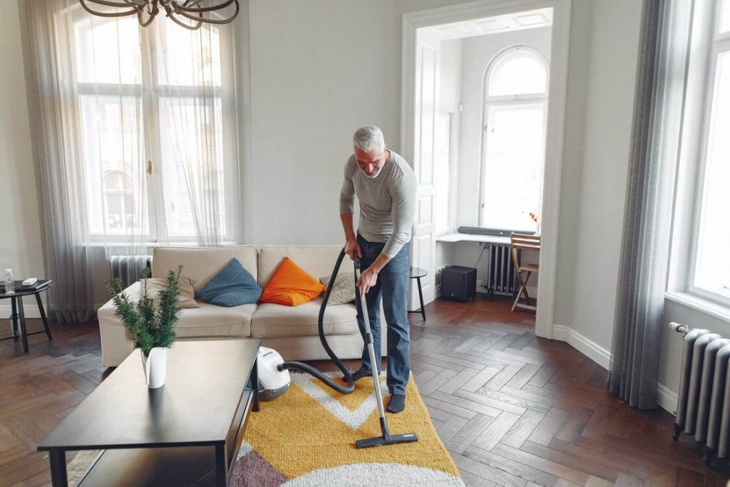 a man vacuuming the living room after cross-country moving