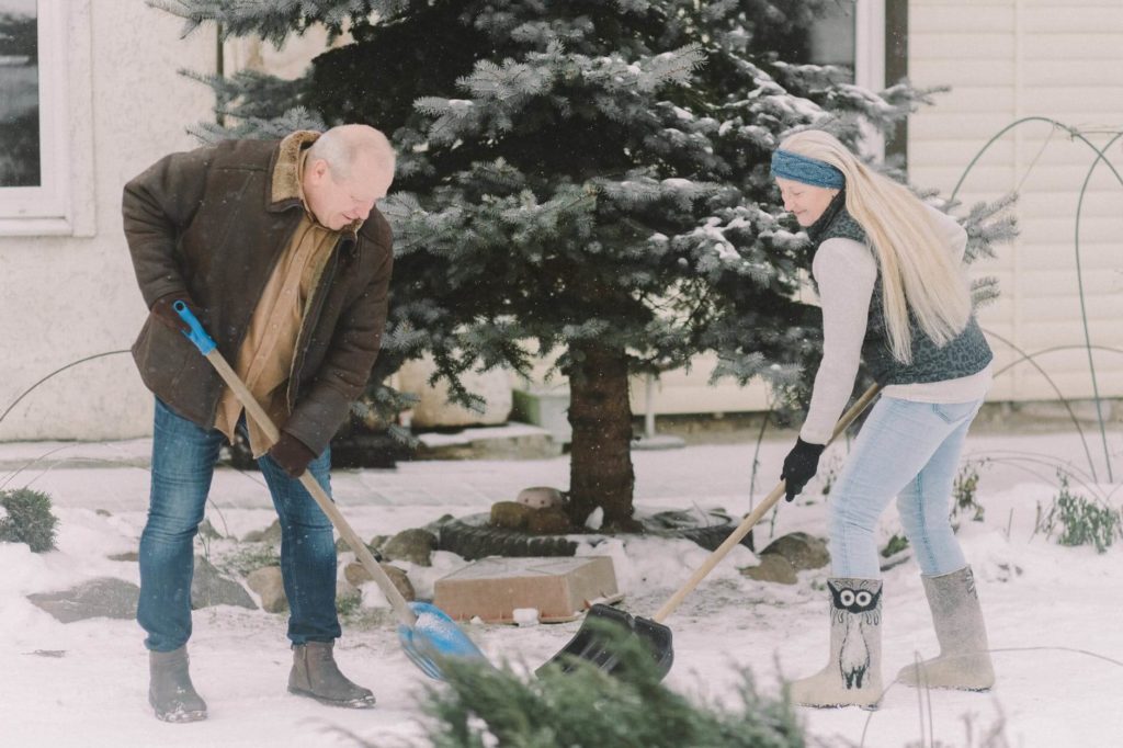 Man and woman shoveling a doorway before long-distance movers arrive 