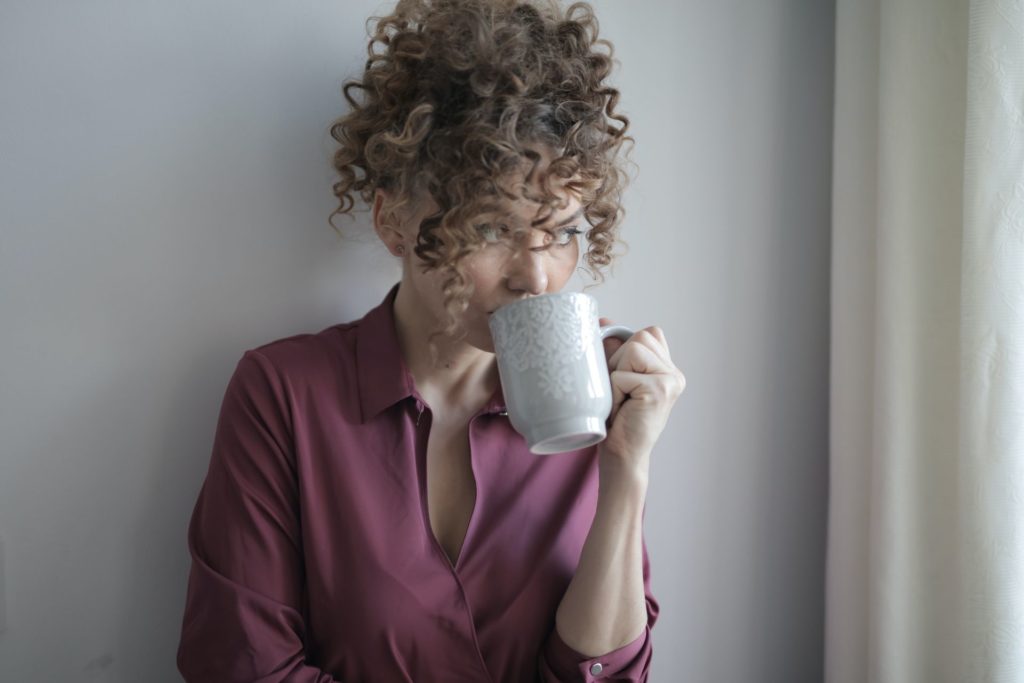 A woman drinking coffee from a mug before long-distance moving