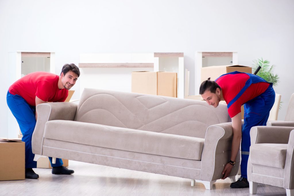 Two professional long-distance movers lifting a heavy couch
