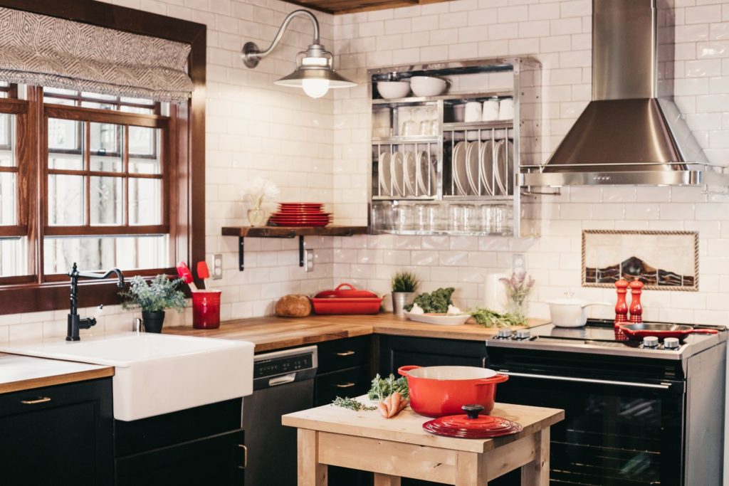 a modern black kitchen with red accents, like dishes, cooking items, and cutlery