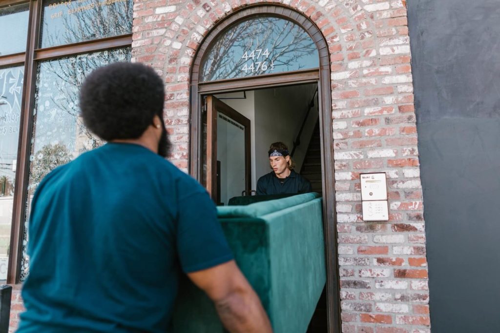 Professional long-distance movers carrying a sofa