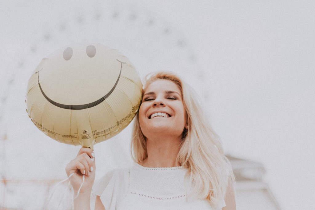 Happy woman holding a smiley balloon