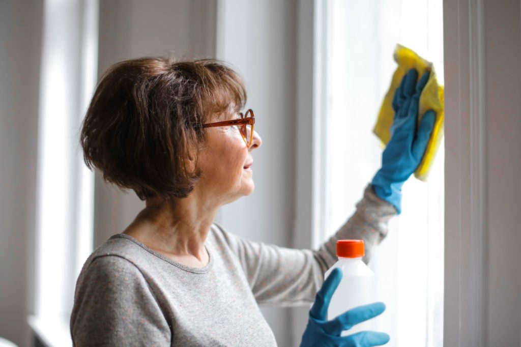 An older woman wiping a window