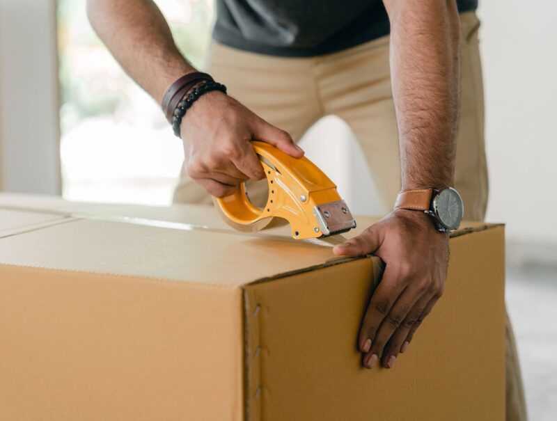 A man applying tape to a cardboard container