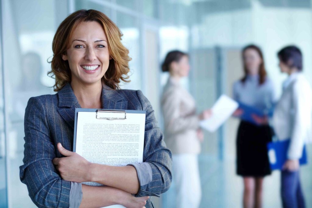 A smiling woman holding papers