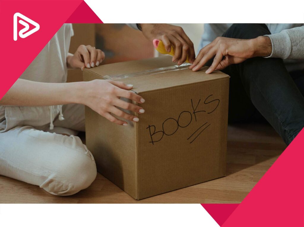 A box labeled 'books' and two people unpacking it