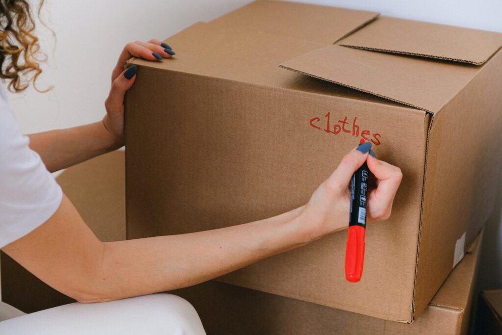 A woman is writing clothes on the box.
