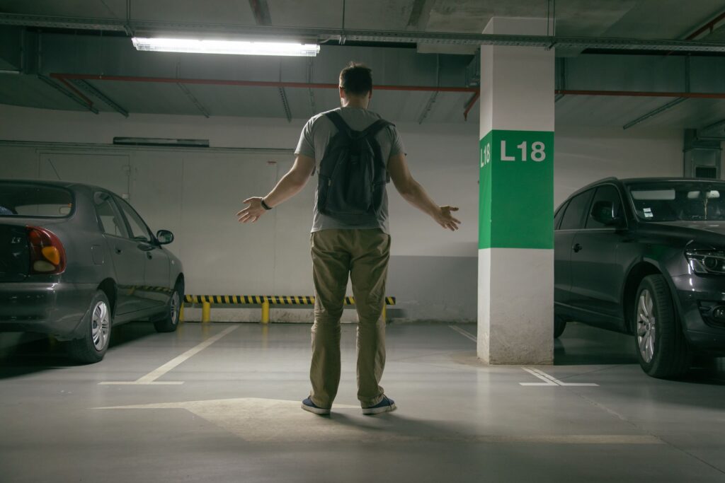 A man with open hands in front of an empty parking space