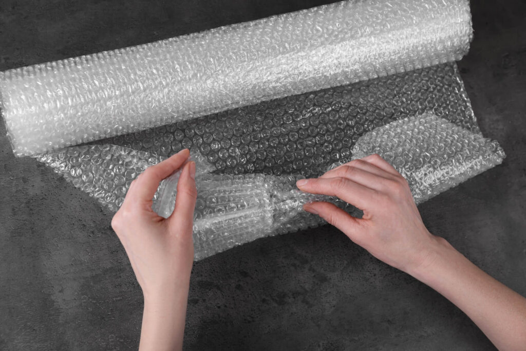 Woman covering wine glass with bubble wrap