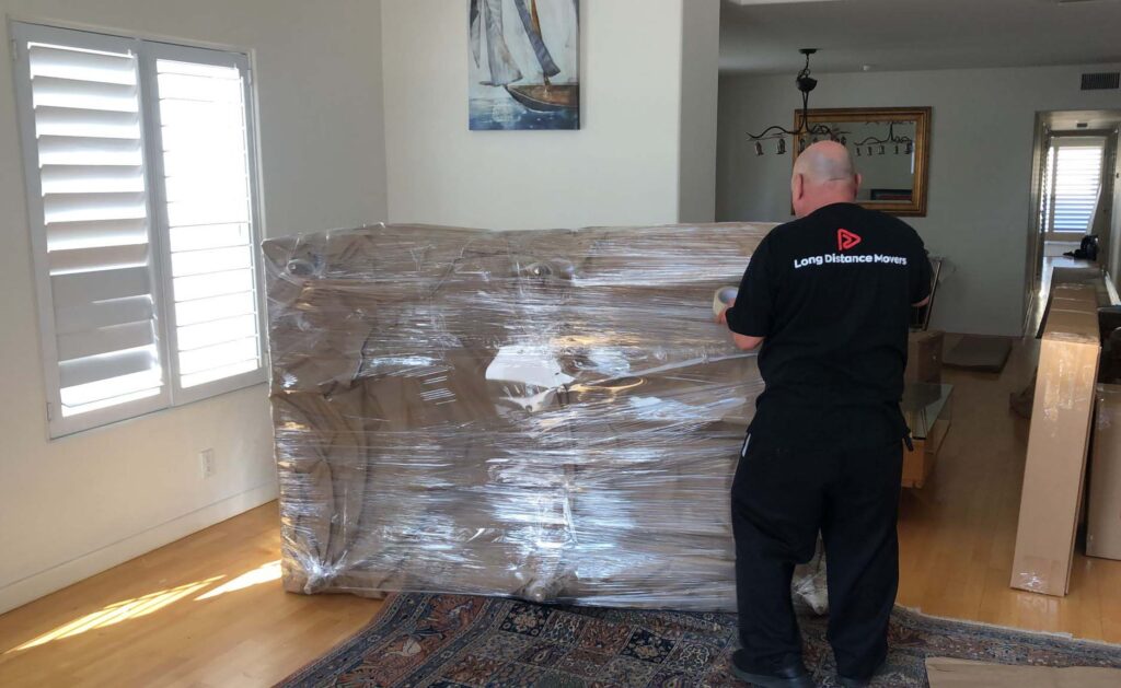 Long-distance movers wrapping a large package