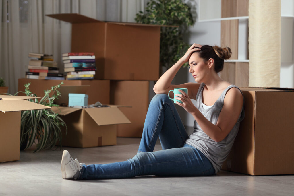 A sad woman sitting on the floor with boxes