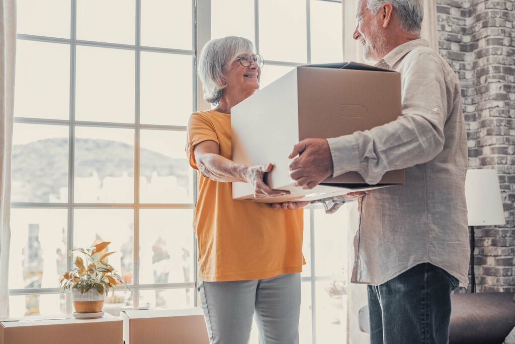 Mature couple carrying boxes when moving into new apartment