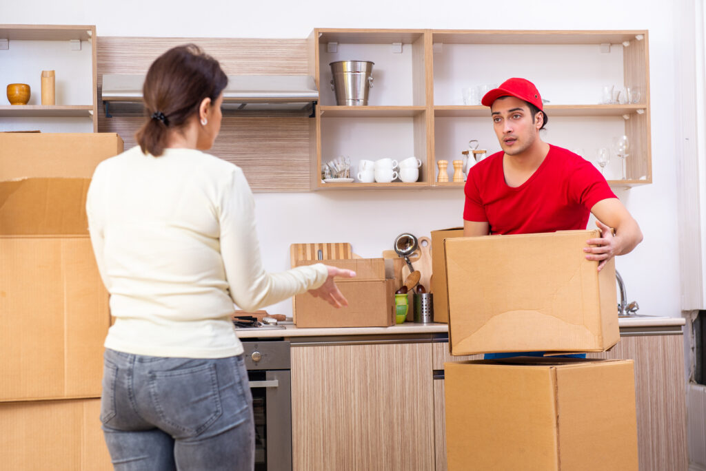 Movers loading boxes while a customer looks concerned